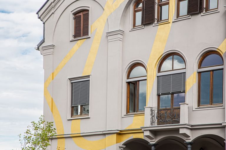 Gold-verzierte Fassade mit rechteckigen und Bogenfenstern